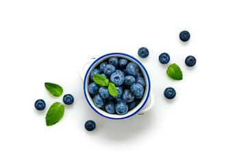Blueberry in ceramic bowl isolated on white. Fresh blueberry closeup, healthy diet concept. Ripe organic bilberry, mint leaf creative composition. Juicy berries background, top view.