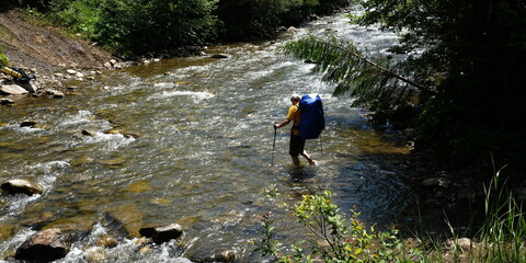 Hiker man crossing the river 