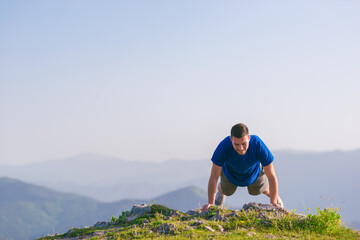 Naklejka na ściany i meble Fit male athlete doing pushups at the edge of a cliff while enjoying the amazing view.