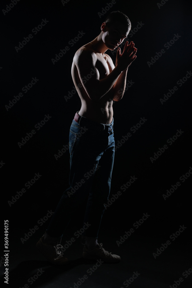 Poster Silhouette picture of a hot shirtless muscular man posing in jeans in a dark studio.