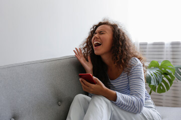 Depressed young woman sitting in her room showing signs of anxiety body language.