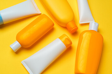 Collection of sunscreen cream bottles on yellow background