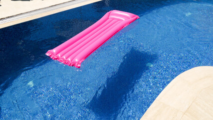 Pink inflatable mattress floating in the pool, holiday and sunny day