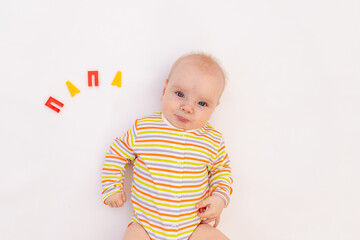 smiling baby girl 6 months old lies on a white isolated background with the inscription Dad in Russian, space for text, top view