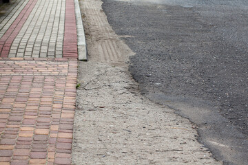Chodnik z betonowych kolorowych kostek wraz z fragmentem asfaltowej drogi. - obrazy, fototapety, plakaty