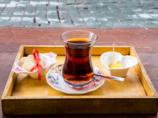 Hot Turkish tea in traditional glass on the wooden table on the street. Relaxation concept