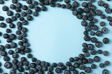 Circle made of blueberries on blue background, space for text