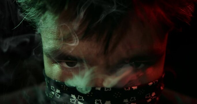 Masked man staring into the camera. Smoky atmosphere.