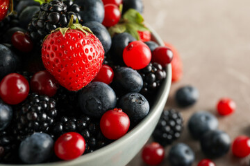 Bowl with fresh berries on gray table, close up