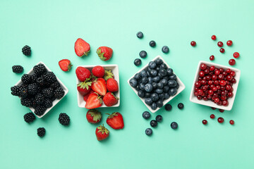 Bowls with fresh berries on mint background, top view