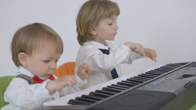 Elegant baby child and his brother feel music, sing and dance together,  children at piano, teamwork