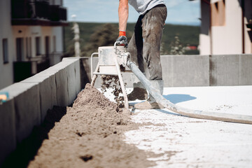 Portrait of worker using sand and cement pump, screed laying and finishing on construction site
