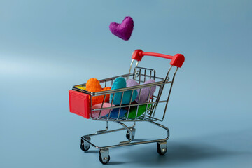 A shopping basket with colorful handmade hearts is on the  a  background. The concept of online shopping, obsession with shopping.