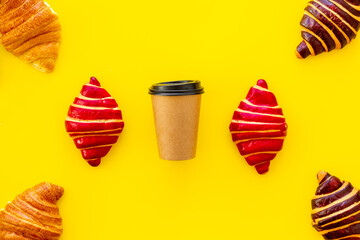 Coffee and croissants on yellow background top view
