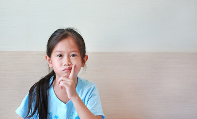Portrait of asian little girl with expression bored face, Child with finger on cheek.