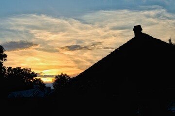 Silhouette of a house roof and trees with a beautifull sunset in the background