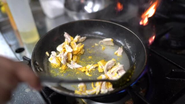 Male hand lighting fire cooking a typical Peruvian food  blue flame on dark background in slow motion