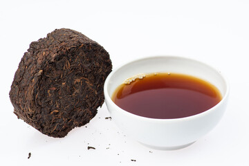 pressed black tea next to a cup of tea on a white background