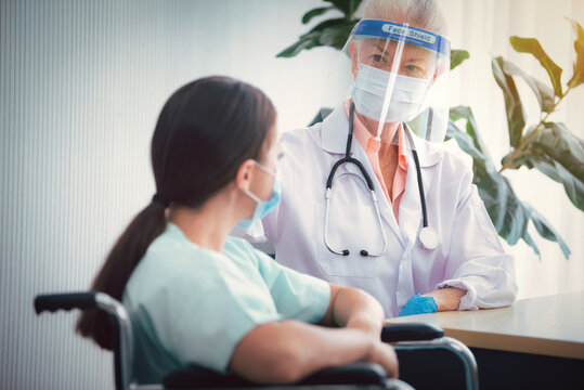 Portrait Of Senior Woman Doctor Wearing Face Shield And Consulting With Women Patient At Room In Hospital. Healthcare Concept