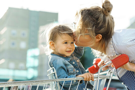 Young beautiful mother and her cute little son in a shopping cart