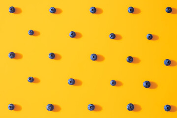 Seamless pattern with fresh sweet blueberry fruit on colorful yellow background. Dessert healthy food concept. Raw summer diet. Delicious nature vegetarian ingredient. Flat lay, minimal style
