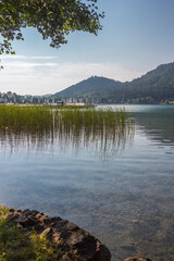 A view of a mountain alpine lake on a summer day. Lake with hills, water and blue sky with clouds. Green forest by the lake in reflection in the water beauty in nature