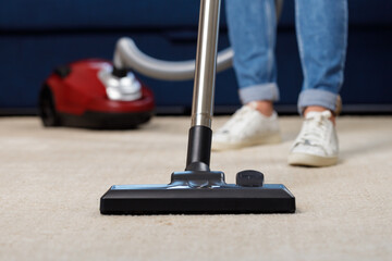 Close up of a woman vacuum-cleaning the carpet