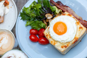 Croque Madame, French Toast with hot grilled ham and cheese with a fried egg on top. Delicious breakfast toast with thinly sliced ham, melt cheese fresh vegetable. Croque Madame with fried egg on top.