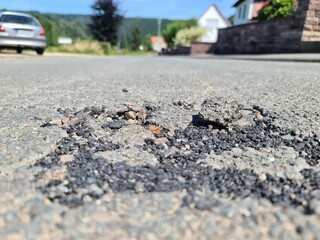 Schäden auf einer Strasse mit losen Asphalt