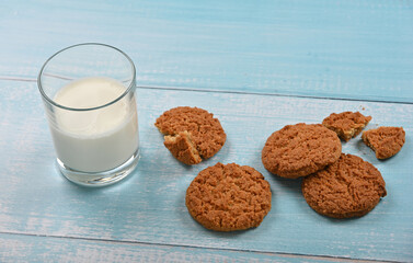 Oatmeal cookies and glass of milk on blue table