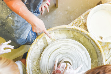 Children making pottery during ceramic lesson with clay