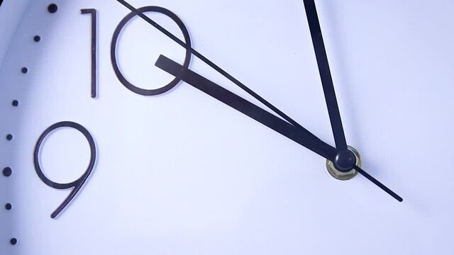Close-up white wall clock face beginning of time 09.55 am or pm, clock minute walk slowly, demonstrating the lack of time. Macro footage. Time, punctual lifestyle, deadline, business concept.