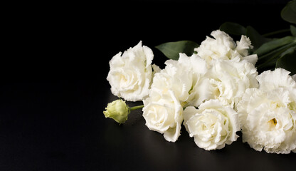 Funeral flowers of white eustoma on a black background. Copy space