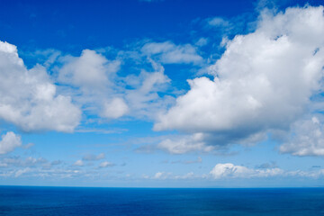 Naklejka na ściany i meble horizonte marino con cielo azul intenso y nubes con forma de algodón blancas
