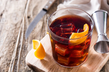Boulevardier cocktail and orange zest on wooden table