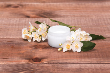 Fototapeta na wymiar Organic cosmetic. Jasmine flowers and cream for face and hand care on wooden background