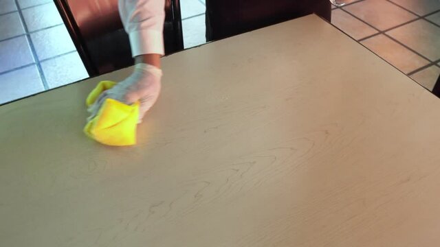 Waiter Cleaning The Table With Disinfectant Spray And Microfiber Cloth In Restaurant