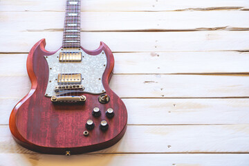 Red and white electric guitar on a white wooden table, with copy space.