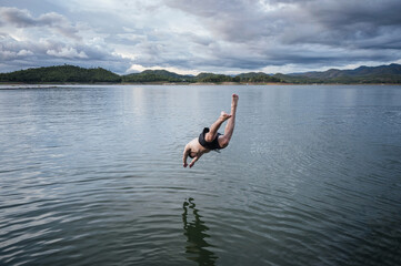 Young man diving into lake in dam