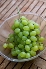 Close up of a bowl with some delicious green grapes on a wooden background