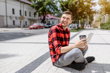 Obraz premium Young man freelancer is working outdoors on his computer laptop