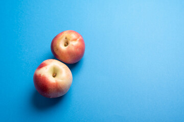 Nectarines flat lay over blue desk. Two nectarines and big blue copy space area. Ready for adding text