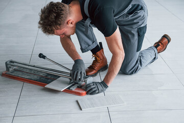 Man in grey uniform installing plate indoors in modern big office at daytime