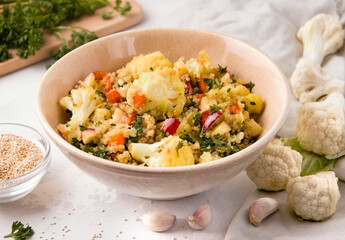 Salad with cauliflower and quinoa on a white plate next to the ingredients