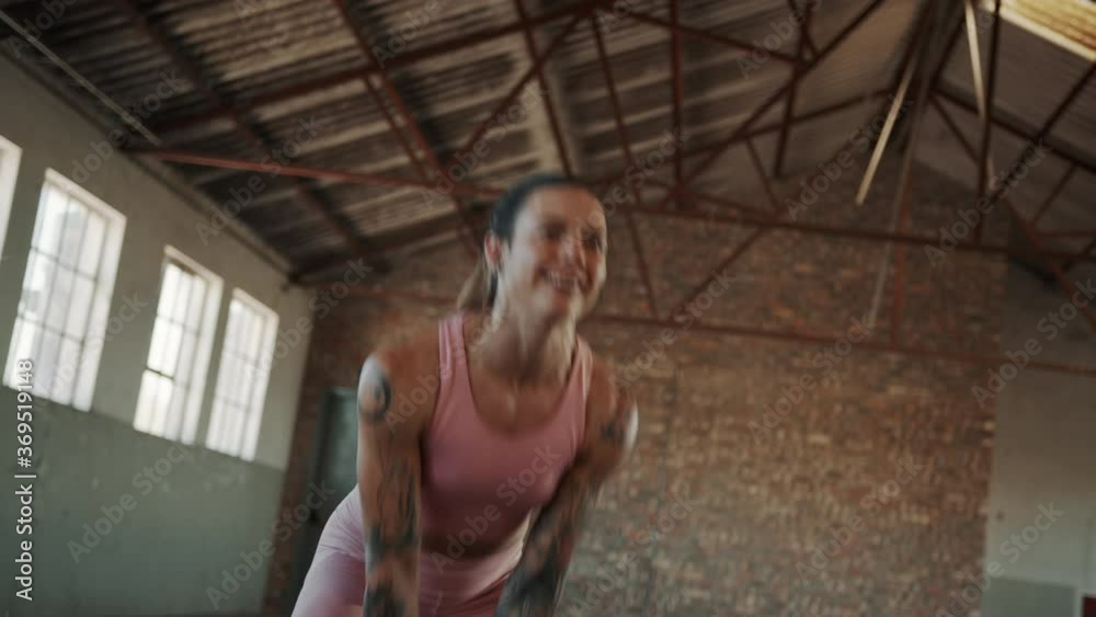 Wall mural Fitness woman working out with kettle bell inside abandoned warehouse. Female with muscular body exercise with kettlebell at cross training gym.
