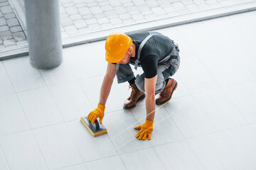 Top view of man in grey uniform that installing plate indoors in modern big office at daytime