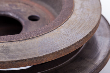 Close-up of element of old brake discs covered with rust on white background in photography studio. Seasonal repair of suspension and braking system in workshop or sale of spare parts for auto parsing