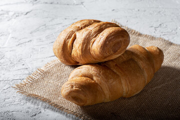 Croissants on the burlap. Two croissants on a concrete background.