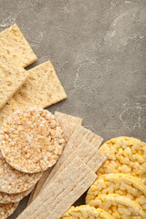 Various types of healthy whole grain crispbreads on grey concrete background. Vertical foto