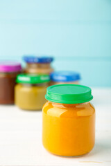 Jars of baby puree on light wooden background